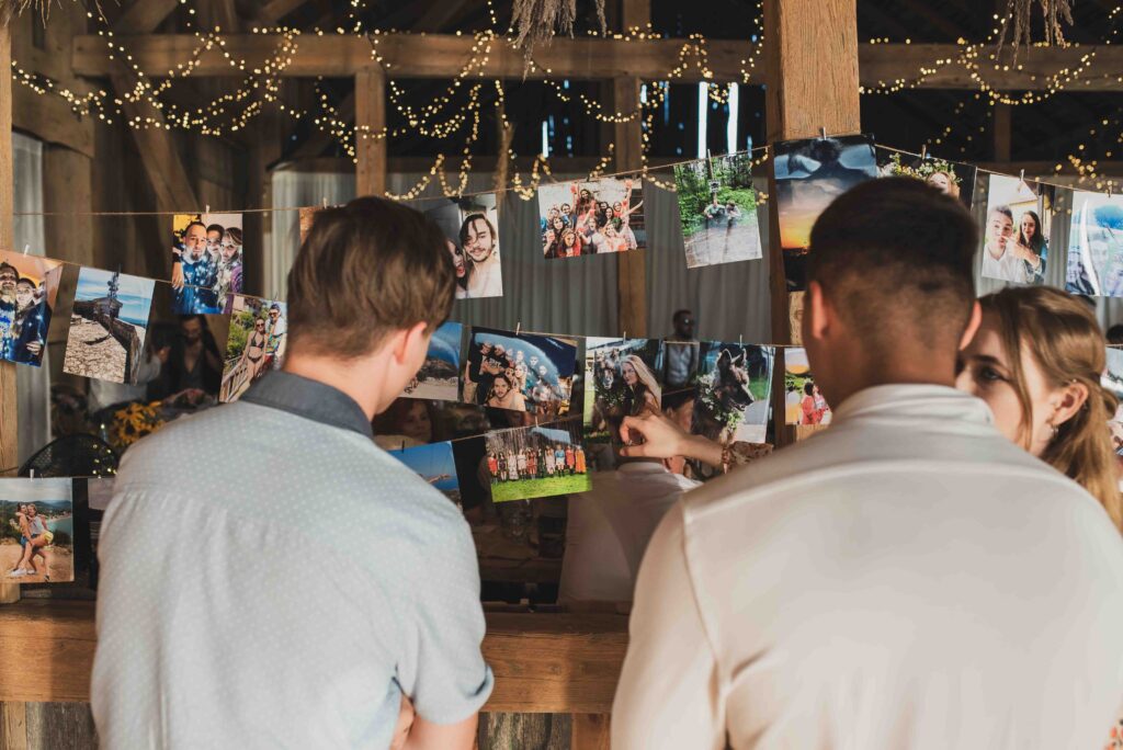 Weselnicy oglądaja pamiątkowe zdjęcia wywieszone na sali weselnej