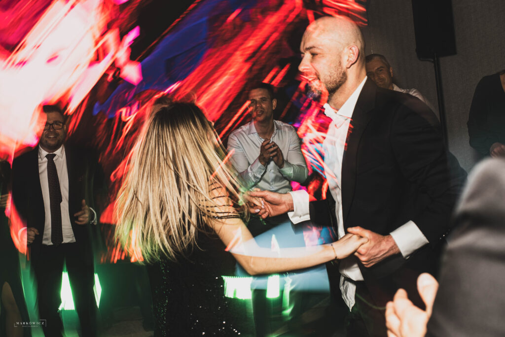 Goście weselni tańczą w świetle reflektorów w hotelu Narvil event