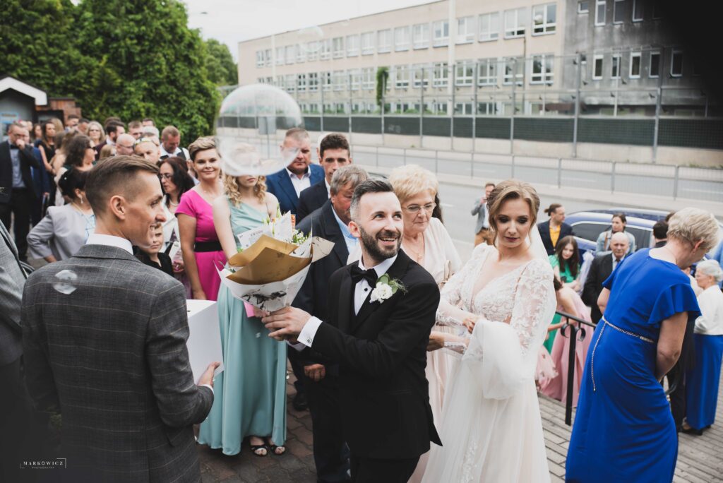 Gość prezentuje bukiet kwiatów z czekoladami przy wyjściu ze ślubu, ceremonia ślubna w Olsztynie