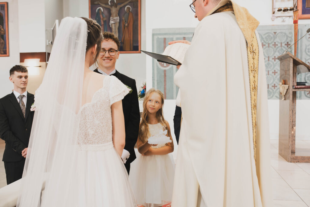 Para młoda w trakcie przysięgi w kościele w Iławie podczas jesiennej ceremonii ślubnej.